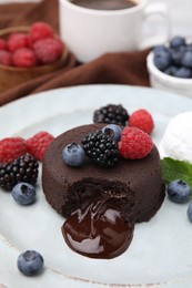 Photo of Delicious chocolate fondant served with fresh berries and ice cream on plate, closeup. Space for text