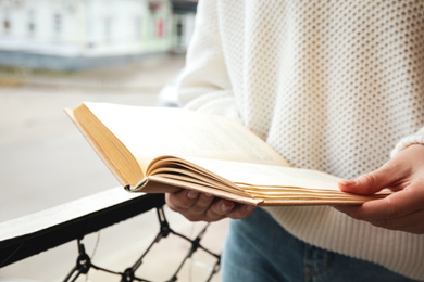 Woman reading book outdoors on sunny day, closeup