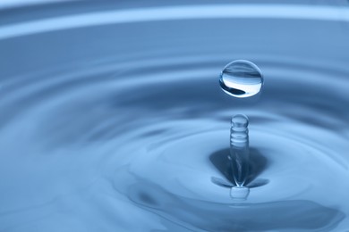 Splash of clear water with drop on light grey background, closeup. Space for text