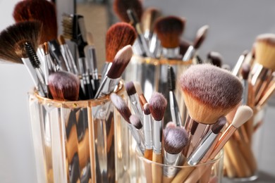Photo of Set of professional makeup brushes near mirror, closeup