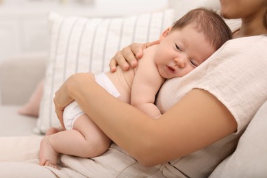 Photo of Mother holding her cute newborn baby on sofa indoors