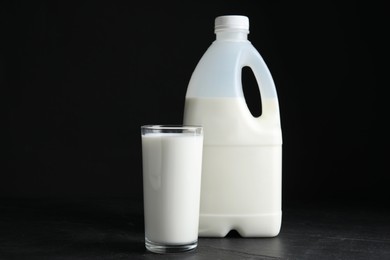 Gallon bottle and glass of milk on black table