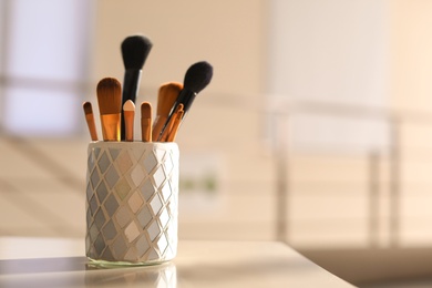 Holder with makeup brushes on table