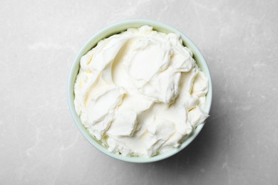 Bowl of tasty cream cheese on grey table, top view