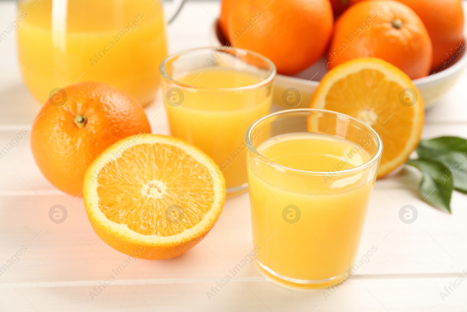 Photo of Delicious orange juice and fresh fruits on white wooden table, closeup