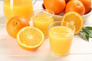 Delicious orange juice and fresh fruits on white wooden table, closeup