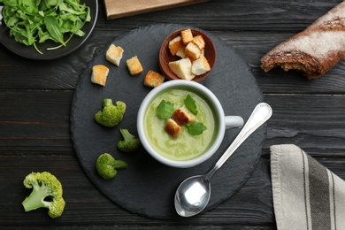 Photo of Flat lay composition with cup of broccoli cream soup on black wooden table