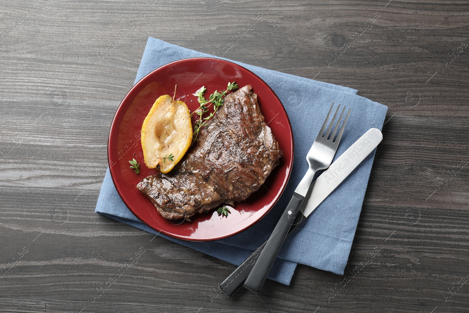 Photo of Delicious roasted beef meat served with caramelized pear and thyme on grey wooden table, flat lay