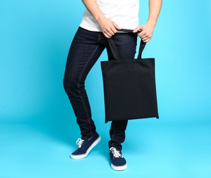 Young man with eco bag on blue background, closeup