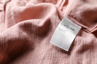 Clothing label on beautiful pink garment, closeup