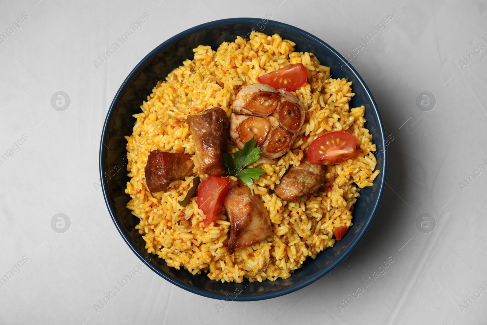 Photo of Bowl with delicious rice pilaf on grey background, top view