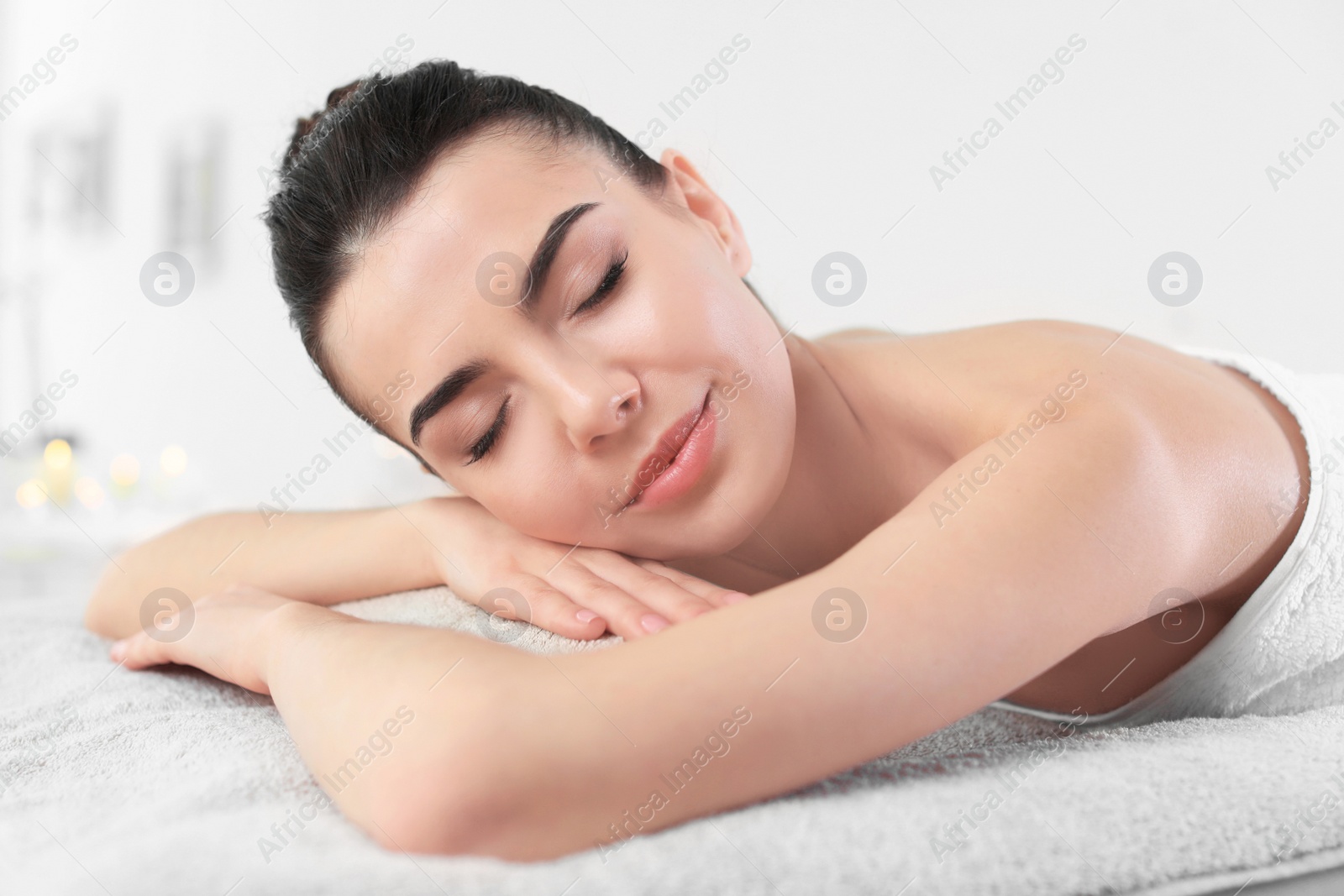 Photo of Young woman lying on massage table in spa salon