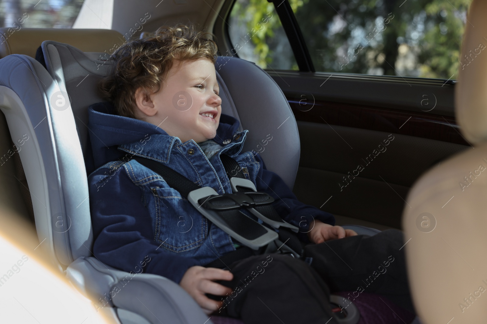 Photo of Cute little boy sitting in child safety seat inside car