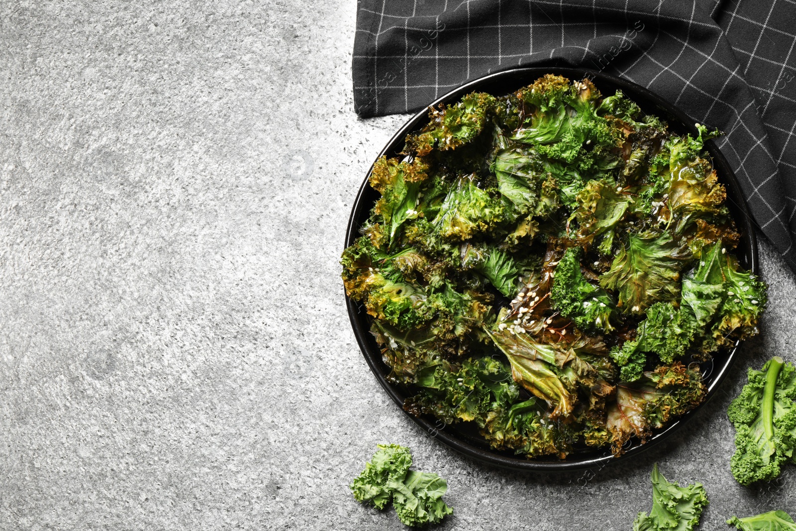 Photo of Tasty baked kale chips on grey table, flat lay. Space for text