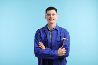 Professional repairman holding hammer on light blue background