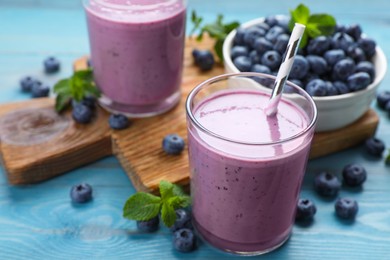 Photo of Glass of blueberry smoothie with mint and fresh berries on turquoise wooden table, closeup