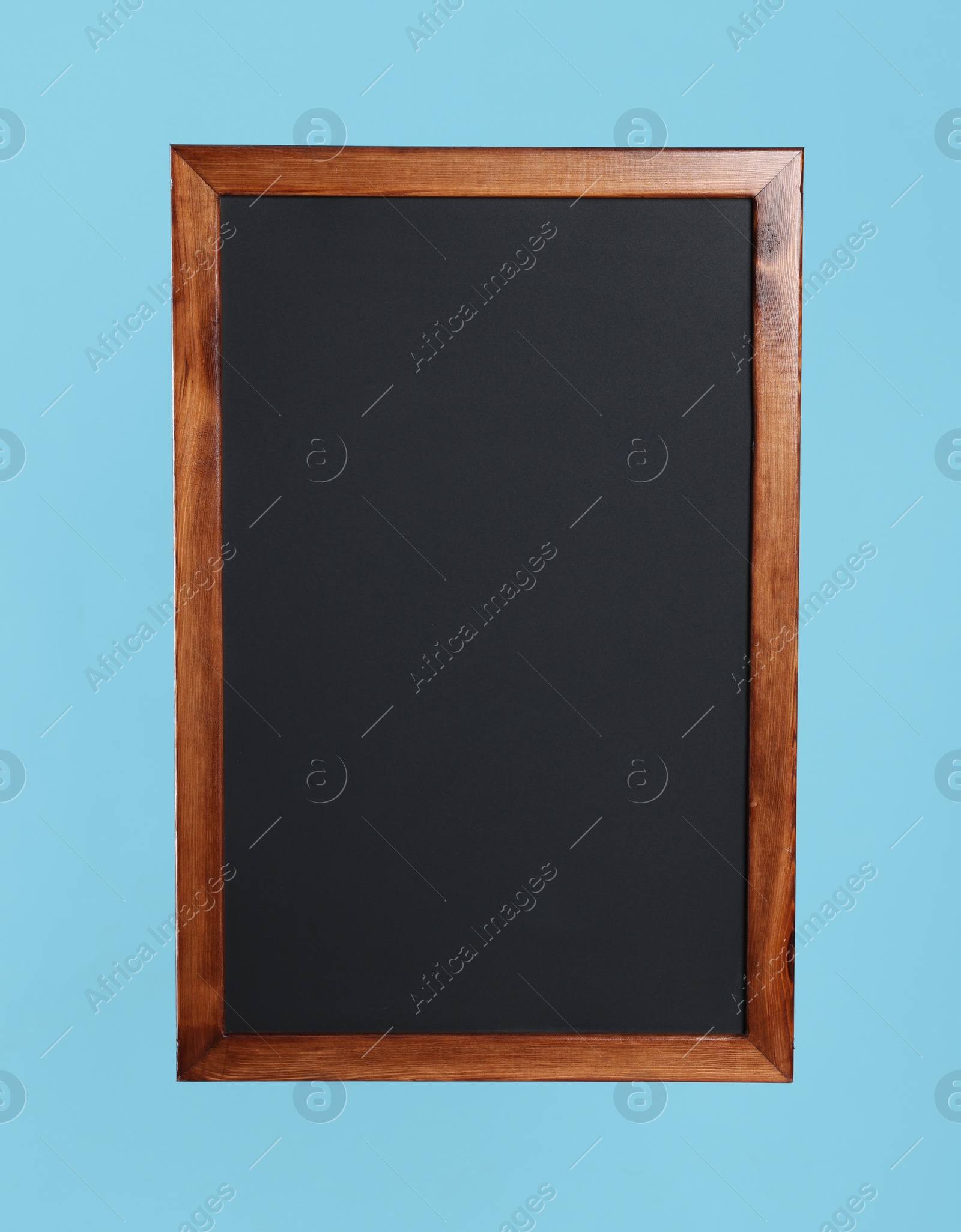 Photo of Clean black chalkboard on light blue background
