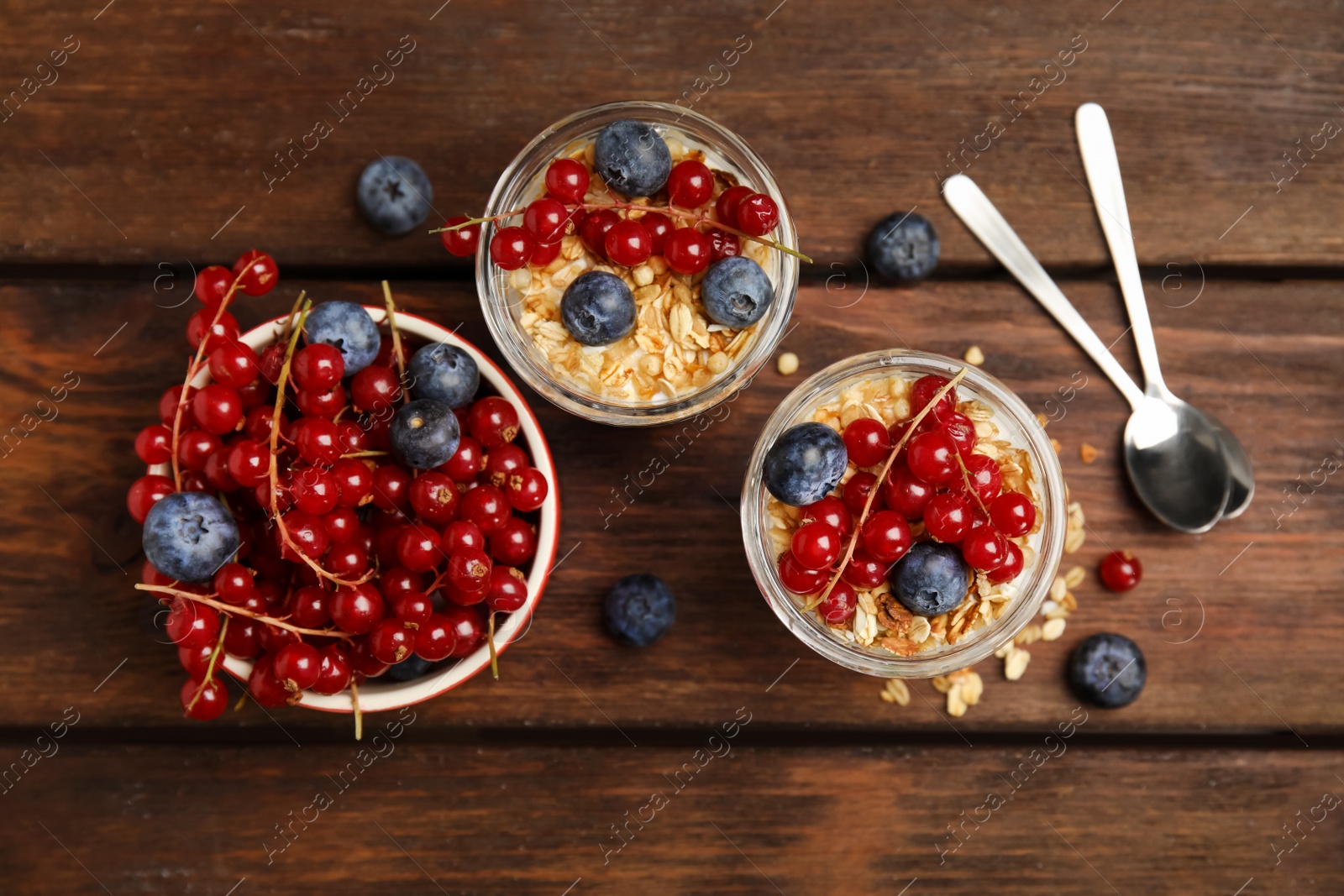 Photo of Delicious yogurt parfait with fresh berries on wooden table, flat lay