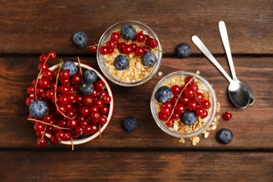 Photo of Delicious yogurt parfait with fresh berries on wooden table, flat lay