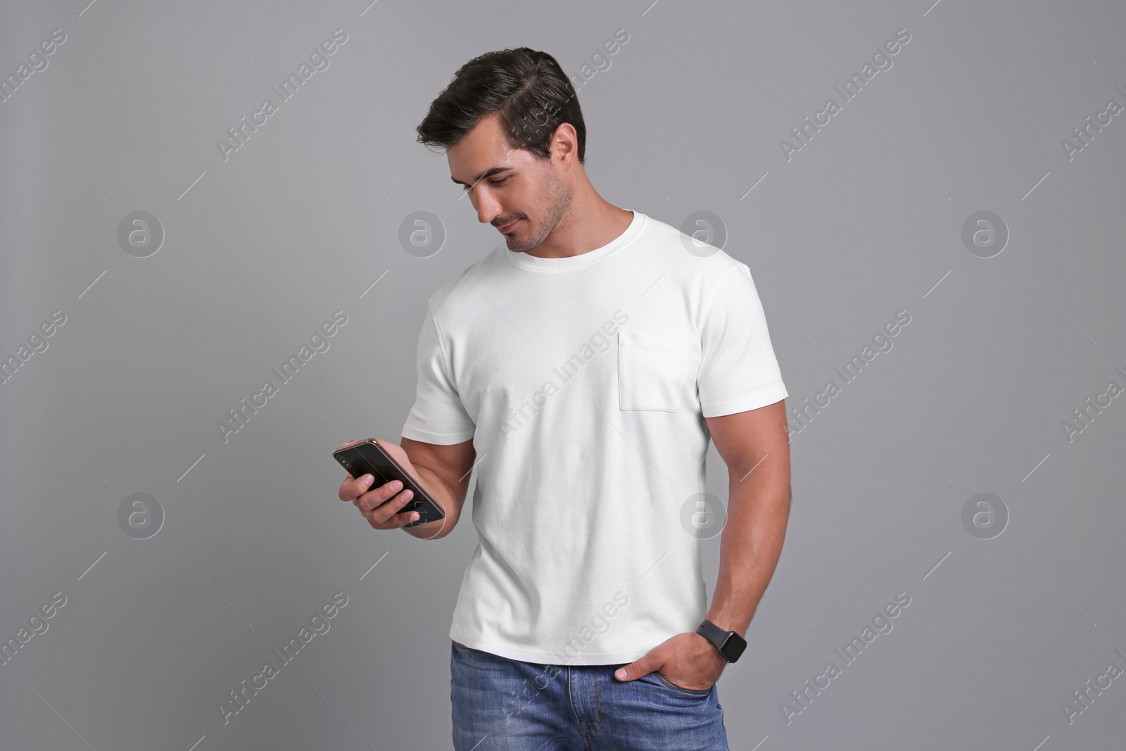 Photo of Handsome young man with smartphone on grey background