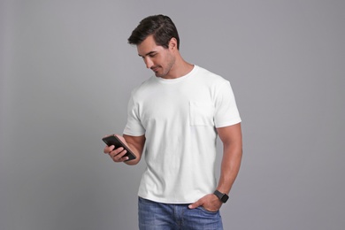 Photo of Handsome young man with smartphone on grey background