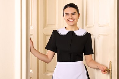 Photo of Portrait of young chambermaid near room door in hotel