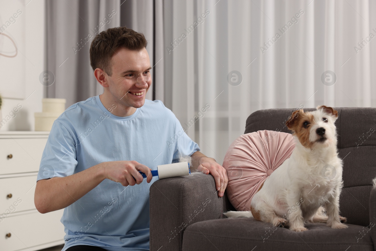 Photo of Smiling man removing pet's hair from armchair at home