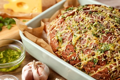 Photo of Tasty homemade garlic bread with cheese and herbs on wooden table, closeup