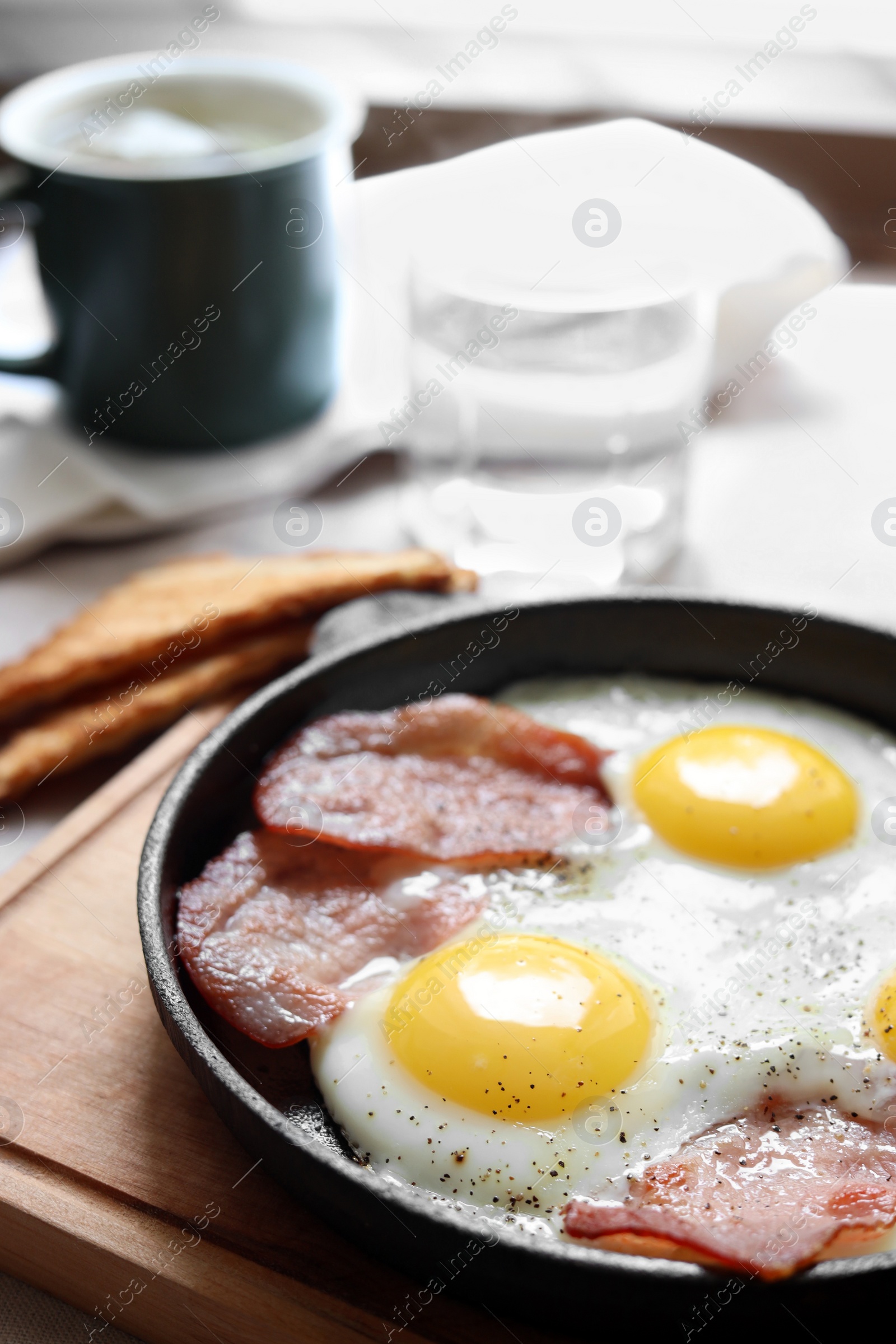 Photo of Tasty fried eggs with bacon on table, closeup. Space for text