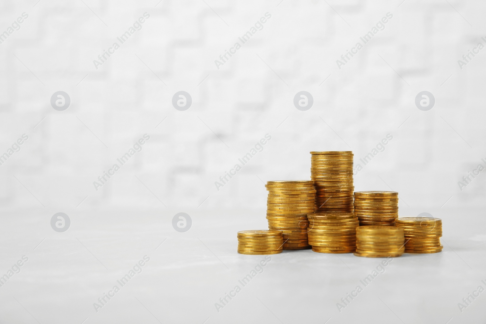 Photo of Many stacks of coins on table against light background, space for text