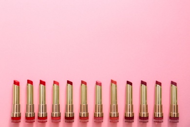 Flat lay composition with different lipsticks on color background, space for text