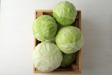 Photo of White cabbage in crate on wooden table, top view