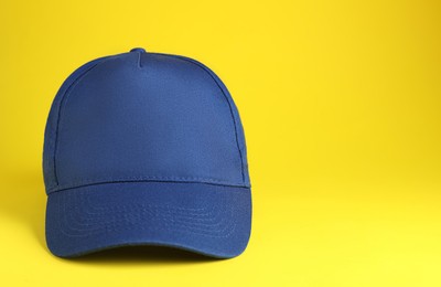 Photo of Stylish blue baseball cap on yellow background. Space for text