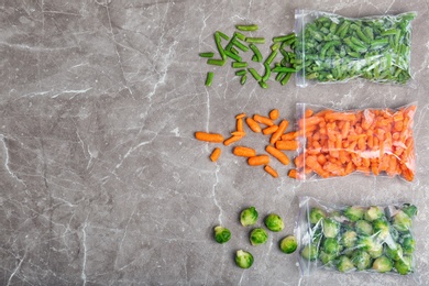 Photo of Plastic bags with different frozen vegetables on table, top view