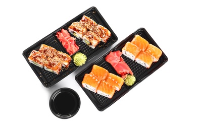 Boxes with tasty sushi rolls and bowl of soy sauce on white background, top view. Food delivery