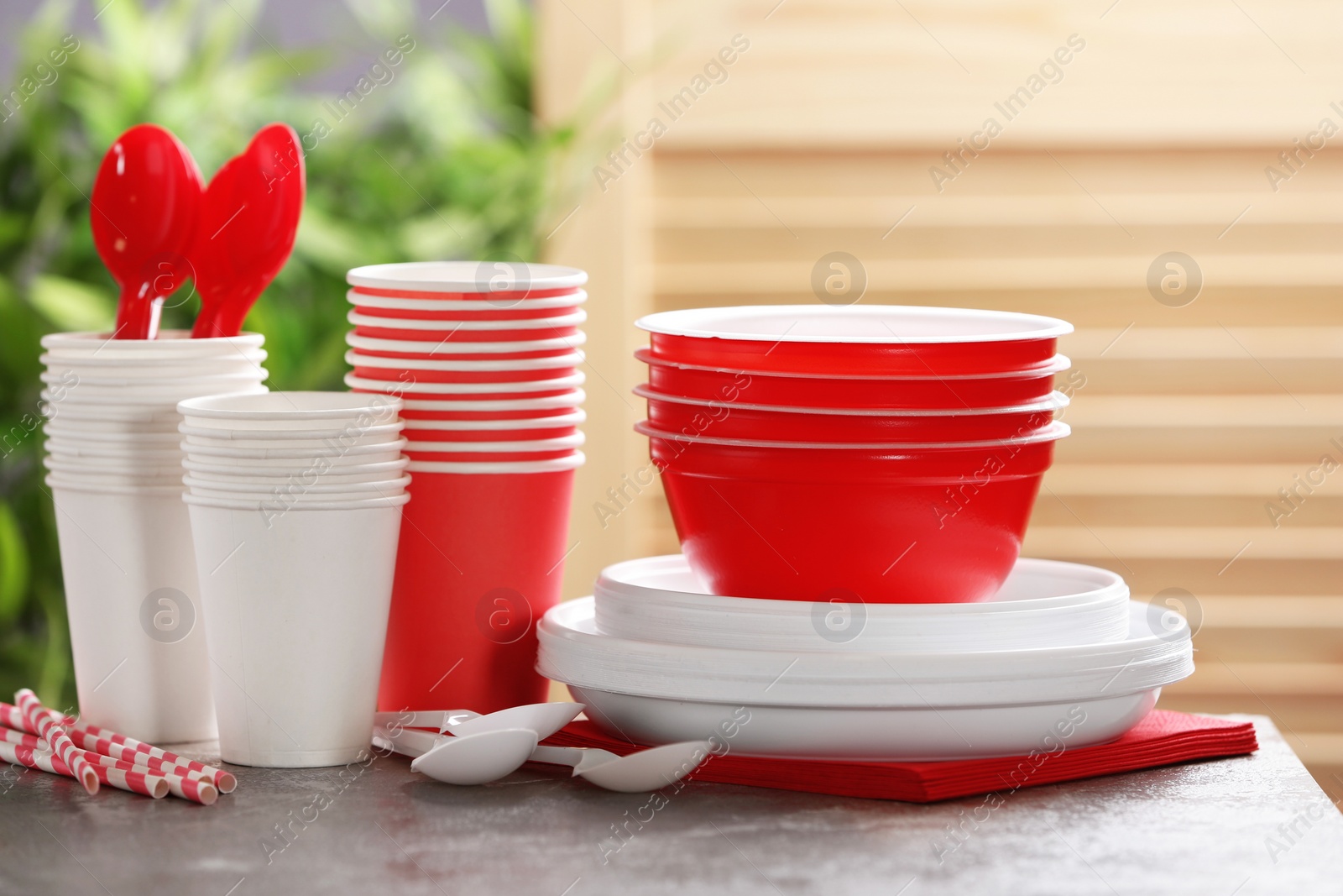 Photo of New plastic dishware on table against blurred background. Table setting