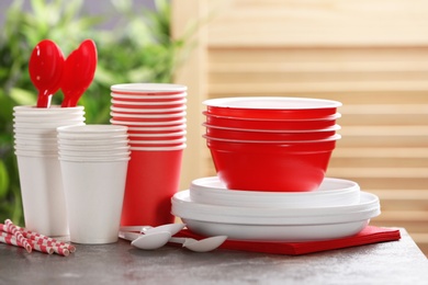 Photo of New plastic dishware on table against blurred background. Table setting