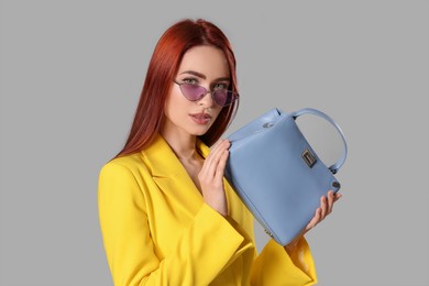 Photo of Stylish woman with red dyed hair and bag on light gray background
