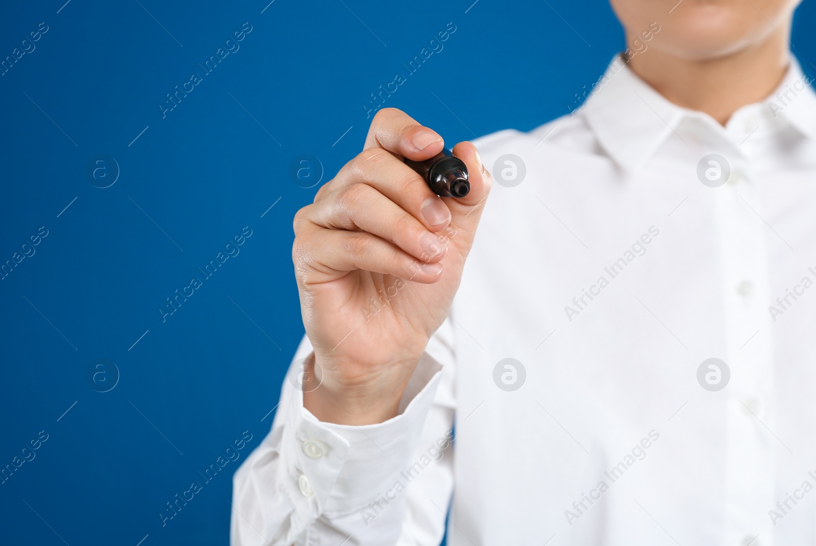 Photo of Woman with marker against blue background, focus on hand