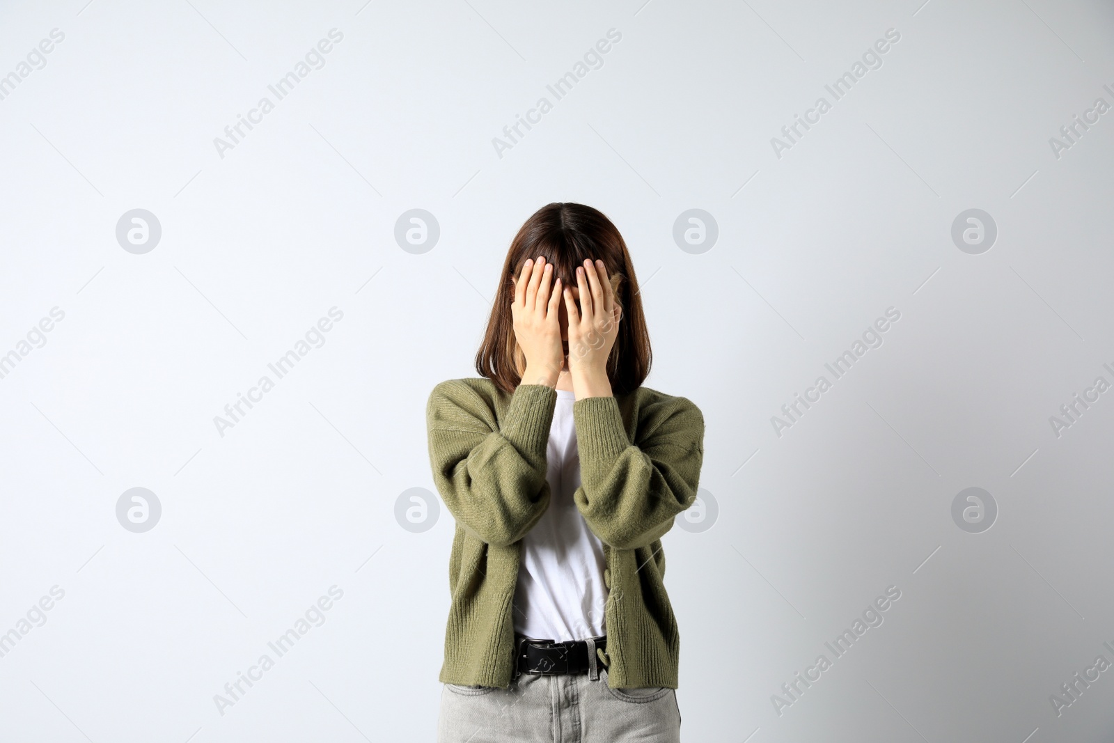 Photo of Young girl hiding face in hands on white background