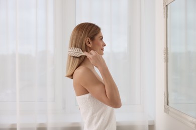 Beautiful woman brushing her hair near mirror in room