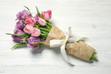 Photo of Beautiful bouquet of colorful tulip flowers on white wooden table, top view