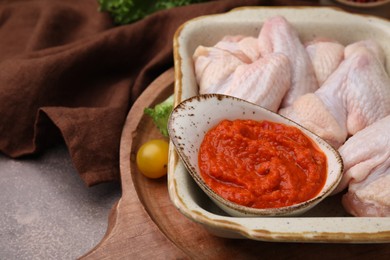 Photo of Fresh marinade and raw chicken on table, closeup