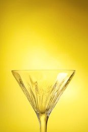 Photo of Elegant empty martini glass on yellow background, closeup. Space for text