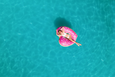 Image of Young happy woman with inflatable ring in swimming pool, top view. Summer vacation