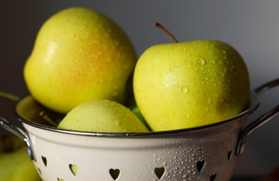 Photo of Fresh wet apples in colander on dark background, closeup