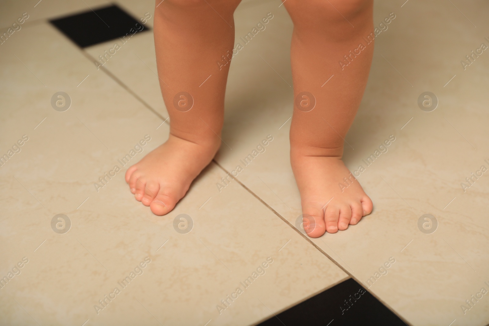 Photo of Cute baby learning to walk indoors, closeup