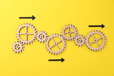 Photo of Business process organization and optimization. Scheme with wooden figures and arrows on yellow background, top view