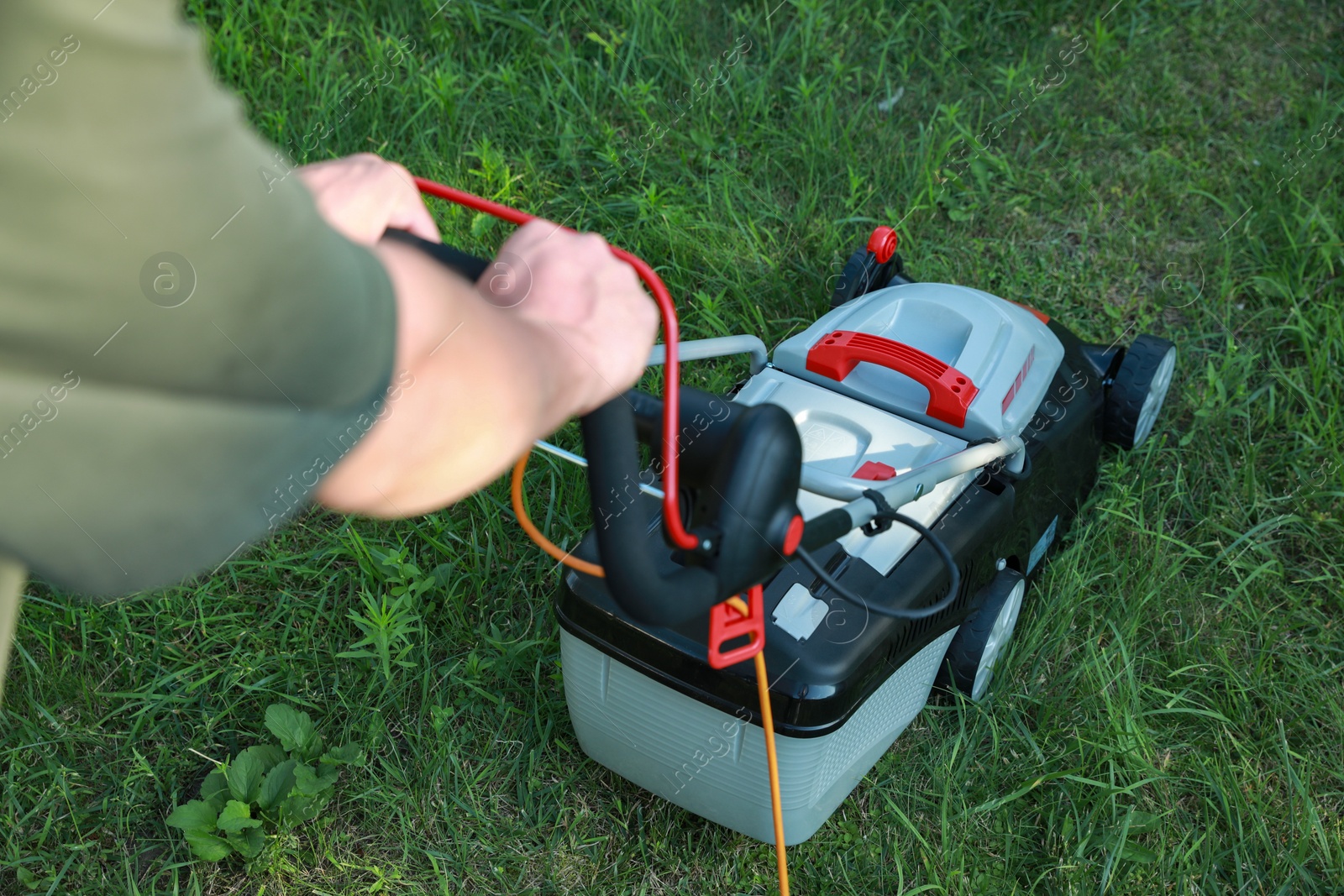 Photo of Man cutting grass with lawn mower in garden, closeup