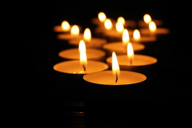 Photo of Burning candles on black background, closeup. Memory day